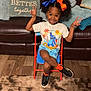 carpet, chair, child, couch, cute, hair_bows, happy, indoor, living_room, peace_sign, person, pillow, playful, portrait, shorts, smiling, sneakers, socks, tshirt, wood_floor