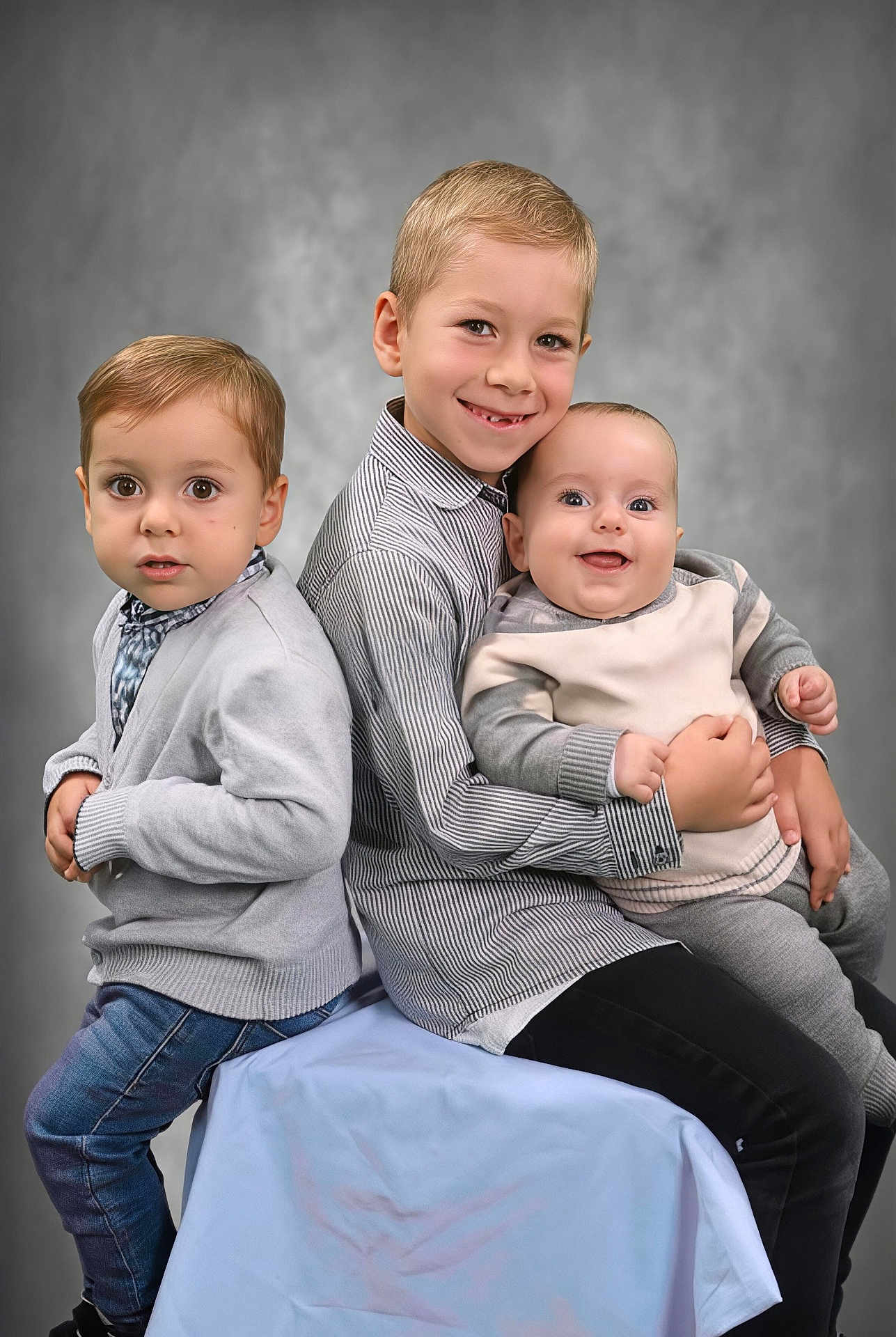 Ezio participe au concours pour gagner de l'argent avec cette photo : child, baby, toddler, portrait, studio, smile, happy, family, siblings, gray_clothing, striped_shirt, jeans, sitting, holding, cute, indoor, background, people, person, photography