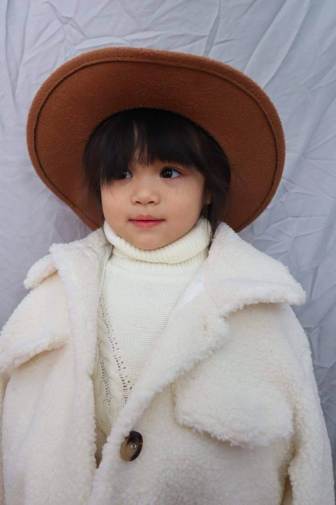 Nan is registered to the contest to win money with this photo: clothing, collar, dress, eyebrow, eyelash, face, fur, fur_clothing, hat, head, headgear, jacket, lip, nose, outerwear, person, skin, sleeve, sun_hat, toddler