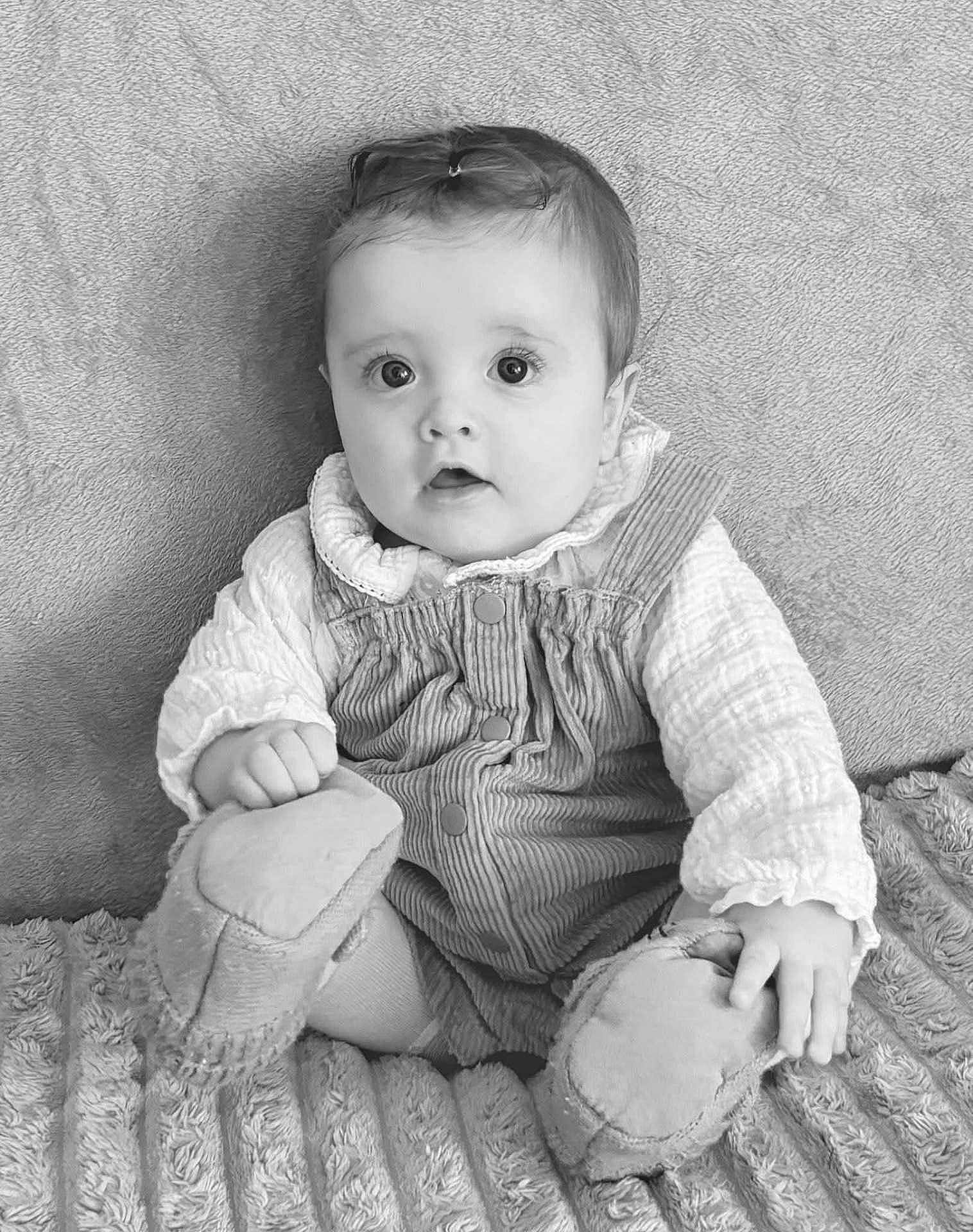 Gabriella participe au concours pour gagner de l'argent avec cette photo : baby, infant, child, portrait, black_and_white, clothing, booties, blanket, texture, sitting, curious, cute, face, eyes, hair, hand, soft, cozy, indoors, person