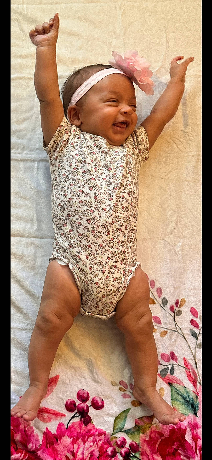 Rayne is registered to the contest to win money with this photo: arms_up, baby, blanket, celebration, cheerful, child, cute, feet, floral_onesie, floral_pattern, flower_headband, happy, indoors, infant, legs, lying_down, newborn, portrait, skin, smiling