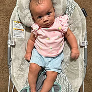 Rayne joined the competition — help win amazing prizes! baby, infant, child, baby_rocker, pink_shirt, blue_shorts, carpet, plush_cushion, patterned_fabric, footwear, barefoot, indoor, cute, portrait, seated, looking_up, curious_expression, soft_texture, baby_clothing, small_hands