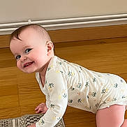 Léna participe au concours pour gagner de l'argent avec cette photo : baby, child, crawling, floor, wooden_floor, onesie, smiling, happy, indoor, portrait, face, hand, knee, cute, infant, person, patterned_clothing, home, rug, skin