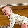 baby, child, crawling, floor, wooden_floor, onesie, smiling, happy, indoor, portrait, face, hand, knee, cute, infant, person, patterned_clothing, home, rug, skin