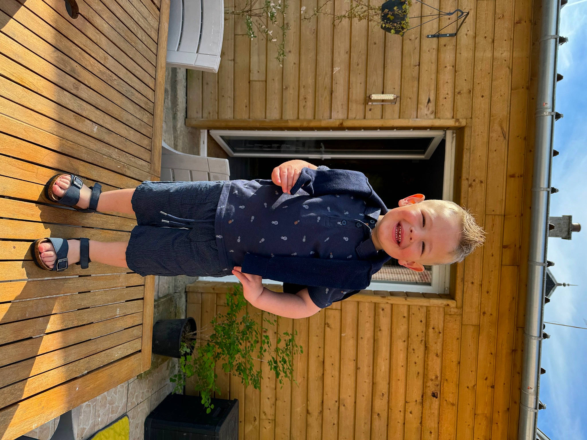 Gabin participe au concours pour gagner de l'argent avec cette photo : denim, door, electric_blue, fun, hardwood, human_leg, joy, leisure, outdoor_shoe, person, plant, siding, sitting, sky, standing, t_shirt, thigh, tree, walking_shoe, wood