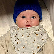Alizée a rejoint le concours — aidez-le/la à gagner de superbes lots ! baby, beige_clothing, bib, blanket, blue_hat, child, closeup, cute, expression, face, headgear, indoors, infant, knitted_hat, looking_at_camera, portrait, soft_lighting, star_pattern, warm_clothing, young_child