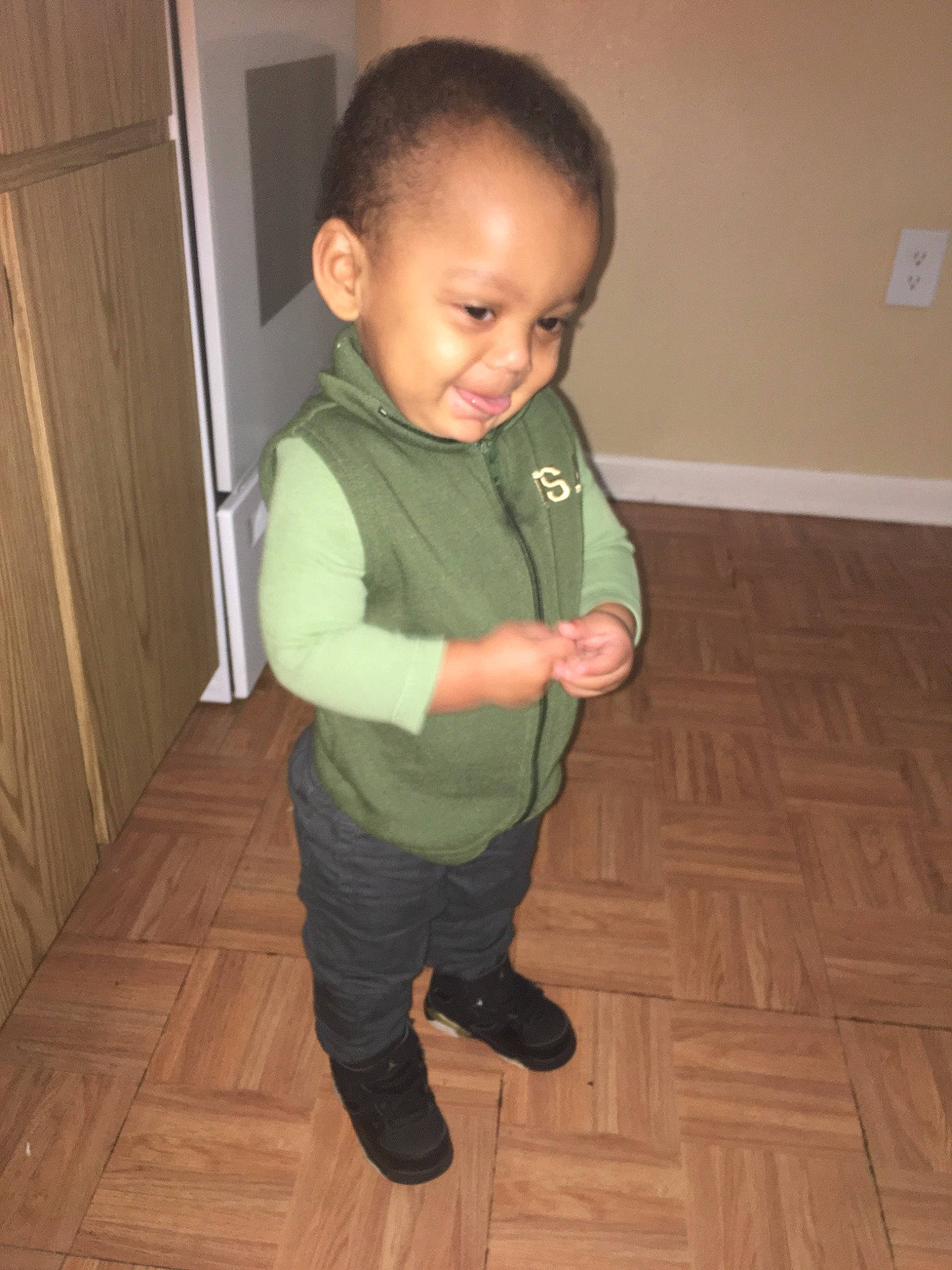 Jessiah is registered to the contest to win money with this photo: arm, child, floor, flooring, joint, joy, leg, person, shoe, shoulder, skin, standing, toddler, wood