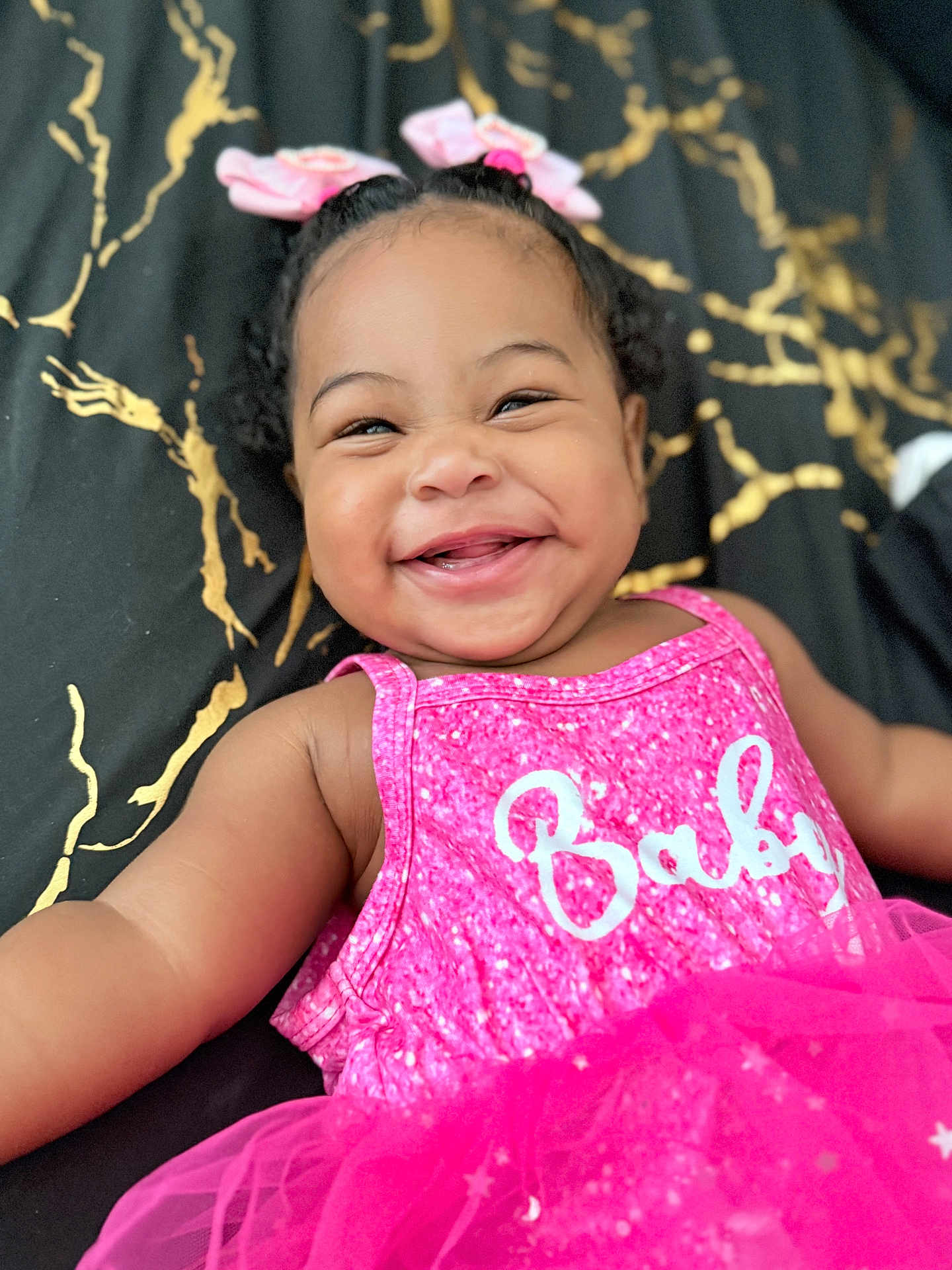 Aisha joined the competition — help win amazing prizes! baby, smiling, pink_dress, bows, happy, child, infant, portrait, closeup, cute, sparkly, lying_down, face, hair, clothing, fabric, gold_pattern, joyful, cheerful, toddler