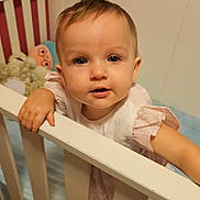 Kayden is registered to the contest to win money with this photo: toddler, crib, child, baby, indoor, nursery, toy, soft_toy, railing, curious, person, face, portrait, pink, white, blue, clothing, cute, hand, exploration