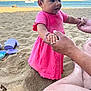 adult_hand, beach, boat, child, happy, nature, ocean, outdoor, person, pink_dress, play, sand, shore, summer, sunlight, support, toddler, toy, vacation, water