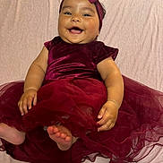 Matahina participe au concours pour gagner de l'argent avec cette photo : apparel, baby, child, cute, dress, fabric, feet, hands, happy, headband, indoors, infant, lying_down, maroon, person, portrait, skin, smiling, soft_texture, toddler