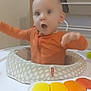 baby, infant, child, orange_clothing, baby_activity_center, toy_piano, indoor, storage_bins, toys, expression, motion_blur, face, head, seat, playtime, home, furniture, baby_toys, child_care, happy
