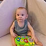 Noah is registered to the contest to win money with this photo: baby, child, toy, chair, indoor, furniture, playing, colorful, curious, infant, person, carpet, plant, fish_tank, home, cute, smiling, sitting, clothing, relaxing