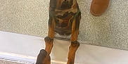 Pepsi is registered to the contest to win money with this photo: dog, mirror, reflection, camouflage_jacket, leash, boots, person, carpet, indoor, curious, pet, animal, paws, standing, looking, small_dog, black_and_tan, legs, closeup, floor