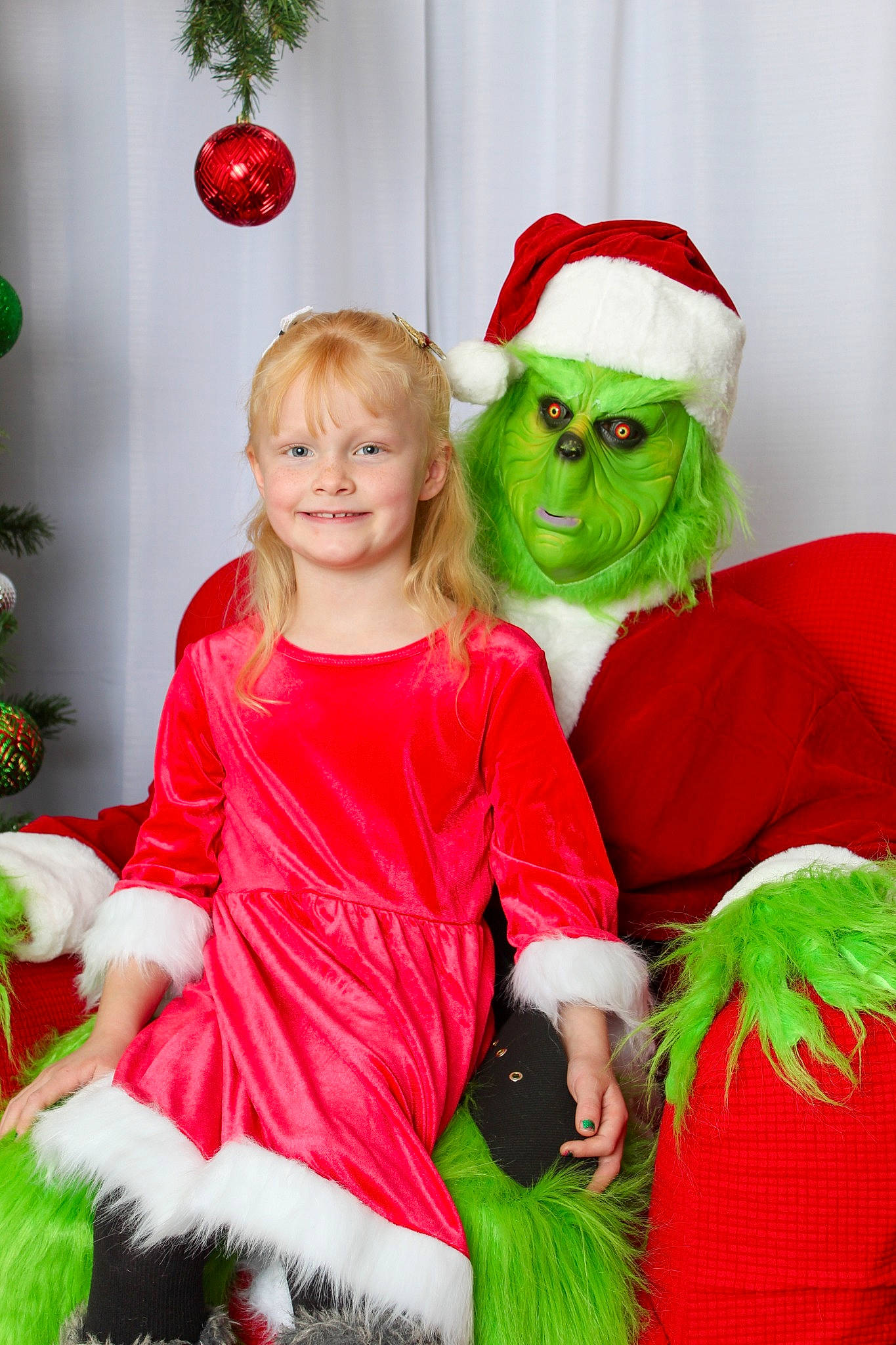 Kassie is registered to the contest to win money with this photo: beard, christmas_decoration, clothing, event, face, facial_expression, fun, green, happy, hat, head, human_body, joy, lap, mammal, person, red, santa_claus, smile, toddler