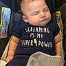 baby, sleeping, child, infant, car_seat, portrait, close_up, face, eyes_closed, dark_clothing, striped_blanket, seat_belt, vehicle_interior, safe, peaceful, cute, shirt_text, superpower, resting, photography