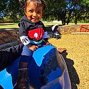 Ximena joined the competition — help win amazing prizes! blue_ride, boots, casual_clothing, child, daytime, fun, grass, happy, hoodie, outdoor, park, person, pigtails, play, playground, smiling, stroller, sunlight, toddler, trees
