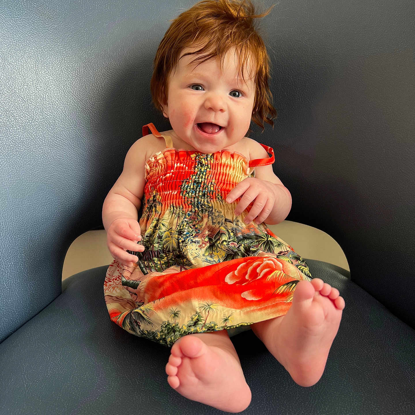 Nilah joined the competition — help win amazing prizes! baby, child, red_hair, smiling, dress, tropical_pattern, sitting, blue_chair, indoor, happy, cute, portrait, barefoot, infant, person, skin, furniture, head, expression, light