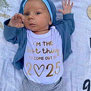 Ryker joined the competition — help win amazing prizes! baby, baby_garment, blanket, blue_hat, casual_wear, child, clothing, cute, expression, face, gray_pants, hand, indoor, infant, lying_down, newborn, onesie, portrait, soft_texture, young