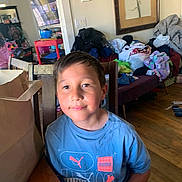 Jesse joined the competition — help win amazing prizes! child, boy, blue_shirt, puma, smiling, indoor, table, clutter, clothes, living_room, wooden_floor, chair, can, plastic_bottle, painting, thermostat, television, mirror, furniture, home