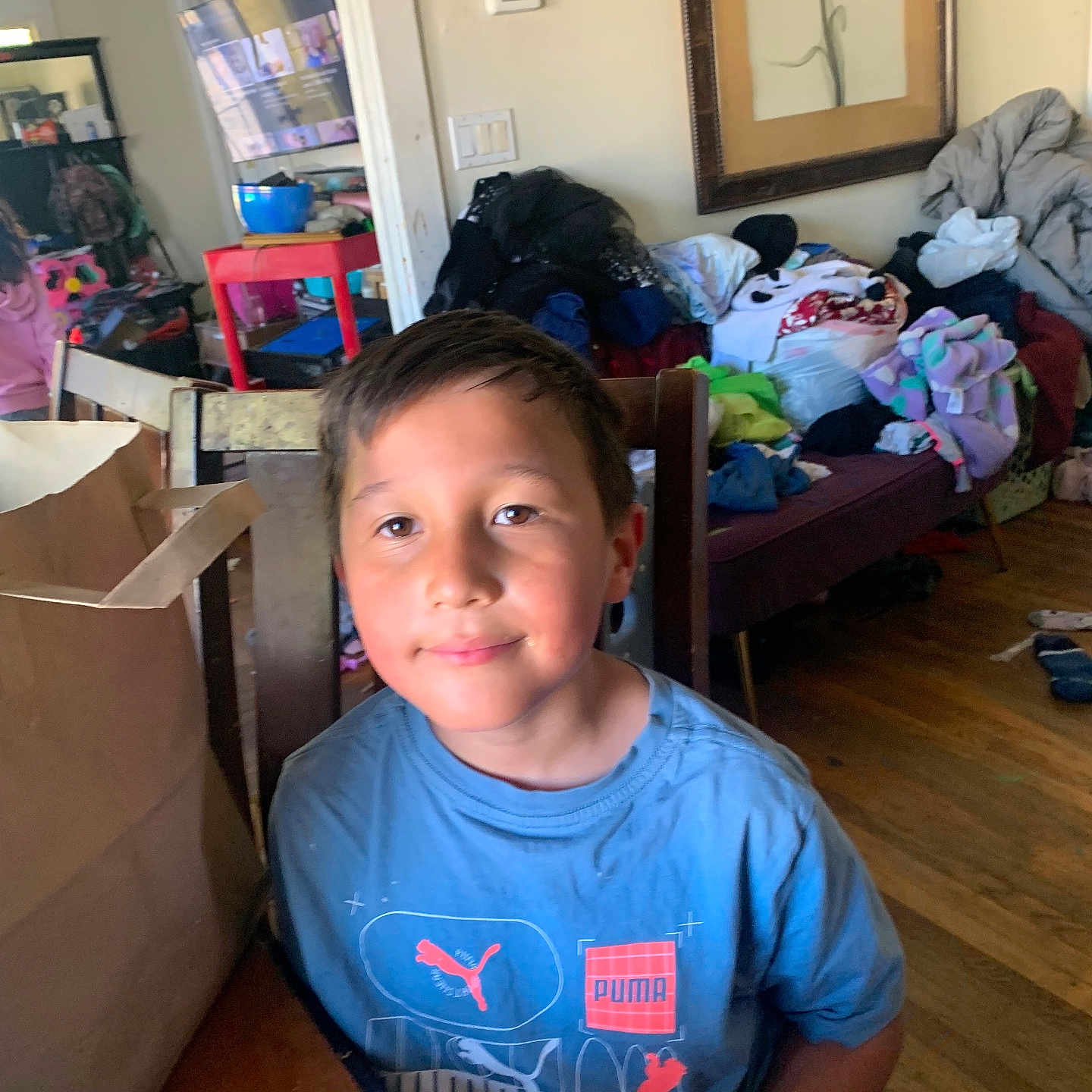 Jesse joined the competition — help win amazing prizes! child, boy, blue_shirt, puma, smiling, indoor, table, clutter, clothes, living_room, wooden_floor, chair, can, plastic_bottle, painting, thermostat, television, mirror, furniture, home