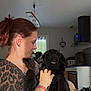 Ava a rejoint le concours — aidez-le/la à gagner de superbes lots ! appliance, black_dog, bracelet, dog, furniture, hair_ponytail, heart_decoration, holding, home, human, indoor, kitchen, leopard_print, natural_light, pet, portrait, side_view, smile, window, woman