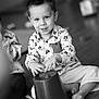 Timéo participe au concours pour gagner de l'argent avec cette photo : child, toddler, boy, smiling, indoors, playing, bucket, barefoot, floor, shirt, long_sleeve, pants, hair, face, hands, candid, black_and_white, expression, toy, fun