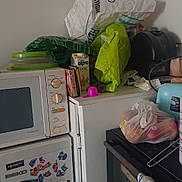 Bobby participe au concours pour gagner de l'argent avec cette photo : appliance, bags, cat_paw, clutter, container, corner, countertop, food_storage, fridge, green_bag, household, juice_carton, kitchen, microwave, miscellaneous, oven, plastic_bag, sticker, towel, wall