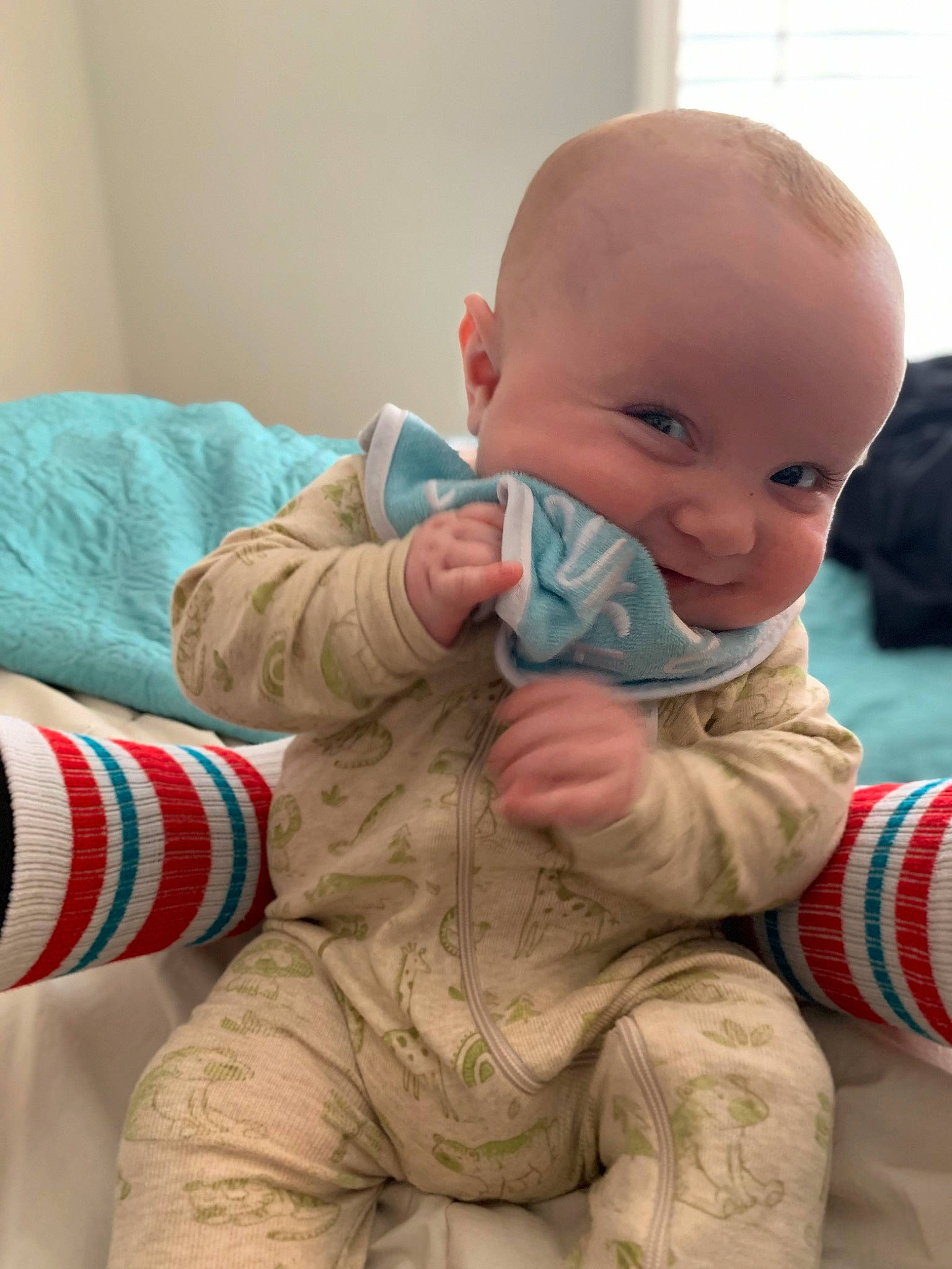Jack is registered to the contest to win money with this photo: baby, baby_toddler_clothing, cheek, child, chin, comfort, finger, flooring, fun, gesture, human_body, linens, mouth, nose, pattern, person, sitting, skin, sleeve, thumb