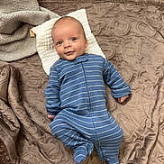 Asher is registered to the contest to win money with this photo: baby, infant, blue_onesie, striped_clothing, blanket, white_cloth, carpet, floor, smile, face, head, lying_down, soft_texture, cozy, indoor, child, cute, young, portrait, baby_clothes