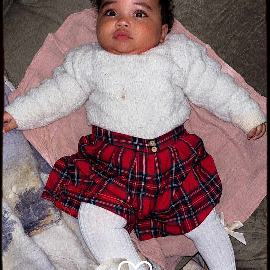 Elvira a rejoint le concours — aidez-le/la à gagner de superbes lots ! baby, blanket, child, couch, crown_emoji, cute, expression, eyes, face, heart_emoji, indoors, infant, lying_down, pink_blanket, plaid, portrait, red_skirt, soft_texture, sweater, white_tights