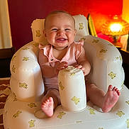 Willow joined the competition — help win amazing prizes! baby, smiling, infant, inflatable_chair, teddy_bear_pattern, pink_clothing, happy, indoors, lamp, warm_lighting, feet, hands, sitting, child, face, expression, room, cozy, toy, furniture