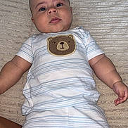 Mylo joined the competition — help win amazing prizes! baby, infant, child, cute, striped_clothing, bear_patch, blanket, lying_down, curious_expression, chubby_cheeks, short_hair, indoors, soft_texture, skin, human, portrait, one_person, relaxed, casual, toddler