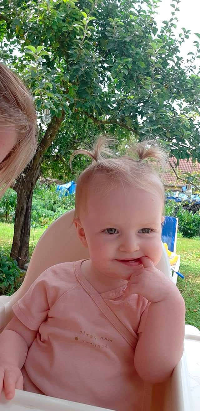 Amelya participe au concours pour gagner de l'argent avec cette photo : baby, baby_toddler_clothing, dress, ear, facial_expression, finger, fun, grass, happy, iris, leisure, lip, neck, person, pink, plant, skin, smile, sunlight, toddler