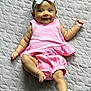 baby, infant, smiling, pink_outfit, headband, floral, lying_down, quilt, textured_bedspread, cheerful, cute, small_hands, small_feet, happy, child, person, indoors, soft_lighting, portrait, one_leg_up