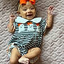 Dolly joined the competition — help win amazing prizes! baby, infant, smile, happy, orange_bow, striped_clothing, ghost_design, quilted_blanket, cute, lying_down, child, portrait, apparel, headband, arm, foot, cute_expression, indoor, soft_texture, playful