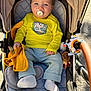 baby, pacifier, stroller, yellow_shirt, blue_pants, blanket, toy, sock, child, outdoor, sunlight, seat, happy, cute, infant, clothing, comfort, playful, baby_toy, relaxation