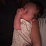 baby, infant, child, hand, arm, onesie, sleeping, thumbsucking, floral_pattern, closeup, human, person, cuddle, peaceful, dim_light, indoor, skin, newborn, resting, quiet