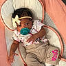 Kyla is registered to the contest to win money with this photo: baby, infant, child, portrait, lying_down, bassinet, cradle, pacifier, headband, lace_bow, socks, clothing, smiling, eyes, indoor, peach_color, textile, furniture, cozy, photography