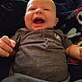 Michael is registered to the contest to win money with this photo: baby, infant, smiling, laughing, clothing, onesie, hand, face, head, blanket, gaming_controller, toy, happy, child, person, indoor, cute, expression, relaxing, comfort