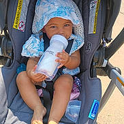 Ellieonna is registered to the contest to win money with this photo: baby, child, stroller, bottle, hat, sunhat, blue, white, clothing, footwear, barefoot, seatbelt, outdoor, sunlight, infant, person, cute, smiling, summer, playtex