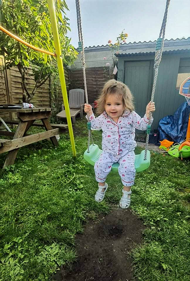 Mylianna participe au concours pour gagner de l'argent avec cette photo : baby_toddler_clothing, biome, botany, city, fun, grass, happy, joy, leisure, natural_environment, nature, people_in_nature, person, plant, playground, public_space, recreation, sky, swing, toddler