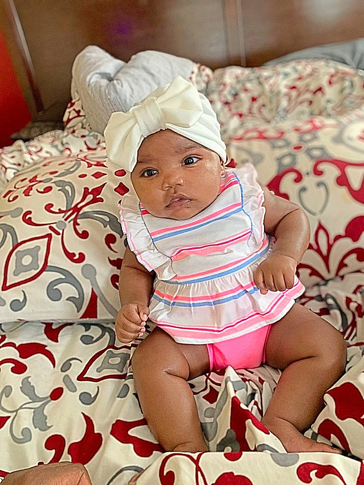 Janiya is registered to the contest to win money with this photo: baby, baby_toddler_clothing, cheek, child, headgear, headwear, leg, person, pink, product, sitting, skin, smile, toddler