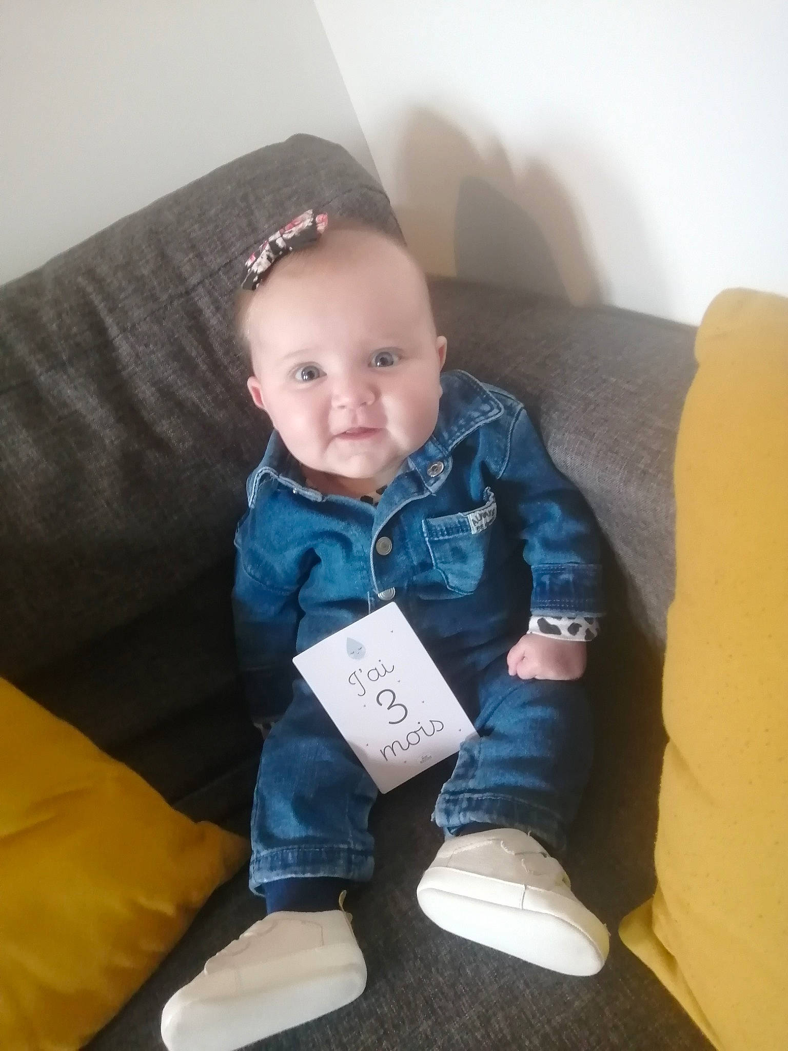 Lou participe au concours pour gagner de l'argent avec cette photo : baby, baby_toddler_clothing, cheek, child, comfort, couch, electric_blue, eye, flooring, fun, happy, knee, leg, person, room, sitting, skin, sleeve, smile, sock