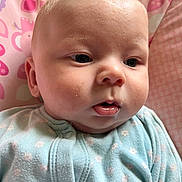 Dexter joined the competition — help win amazing prizes! baby, infant, face, child, onesie, blue_clothing, pink_background, patterned_background, closeup, portrait, chubby_cheeks, curious_expression, soft_skin, indoors, young_child, cute, person, head, small_child, sitting