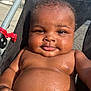 baby, child, water_droplets, stroller, sunlight, smile, skin, face, arm, chubby, outdoor, closeup, infant, seat, black_hair, expression, relaxing, summer, cute, portrait