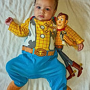 Roman joined the competition — help win amazing prizes! baby, child, onesie, toy_story, woody, doll, blue_clothing, yellow_clothing, plush_toy, bed, blanket, soft_texture, infant, cute, lying_down, portrait, indoor, person, playful, colorful