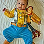 baby, child, onesie, toy_story, woody, doll, blue_clothing, yellow_clothing, plush_toy, bed, blanket, soft_texture, infant, cute, lying_down, portrait, indoor, person, playful, colorful