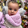 Raelynn is registered to the contest to win money with this photo: baby, child, earmuffs, pink_jacket, fluffy_clothing, indoor, toys, stuffed_animals, colorful_background, closeup, face, portrait, cute, winter_wear, warm_clothing, soft_texture, hand, holding, curious_expression, person
