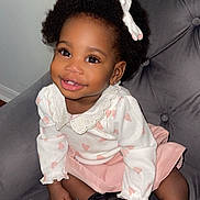 Faith is registered to the contest to win money with this photo: toddler, child, smiling, curly_hair, bow, white_top, pink_skirt, black_shoes, chair, indoor, cute, happy, portrait, fashion, person, seated, baby, hand, face, eyelashes